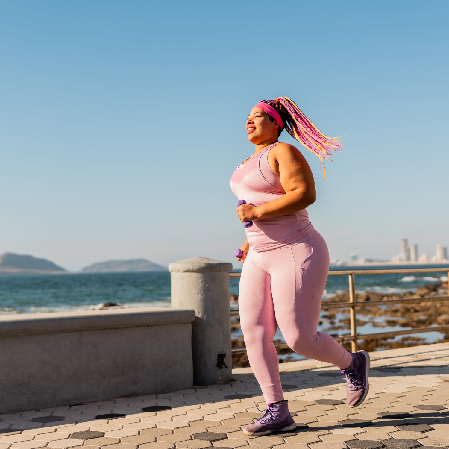 woman running in pink matching set with colorful braids