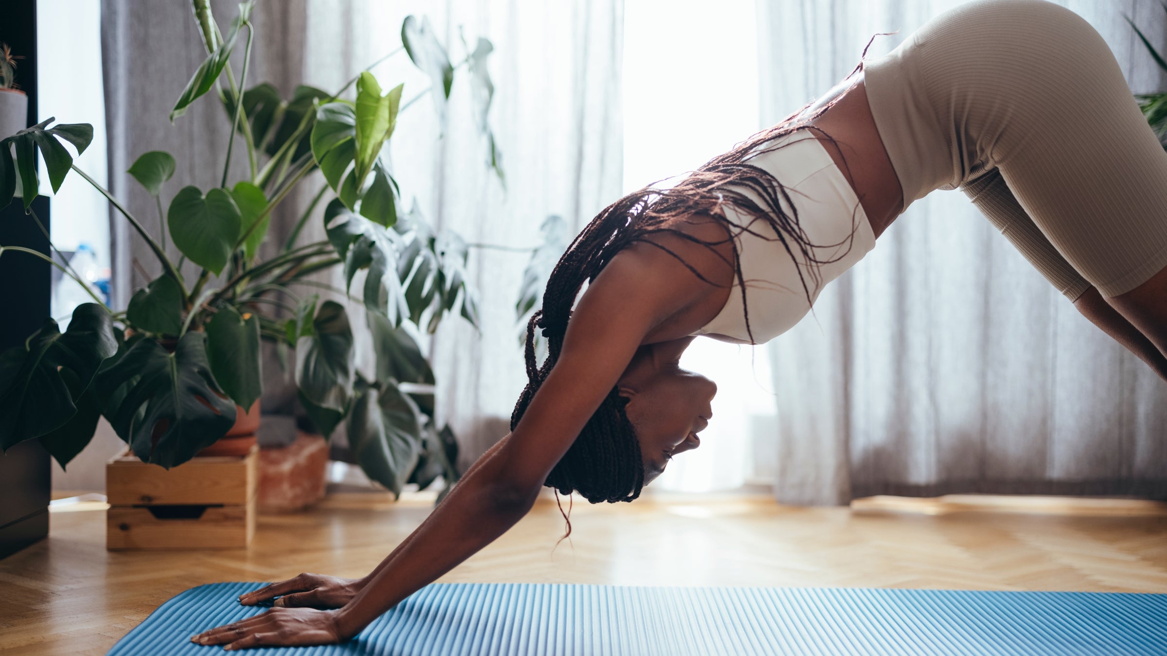 Side view of African-American woman in sportswear practicing yoga in the morning