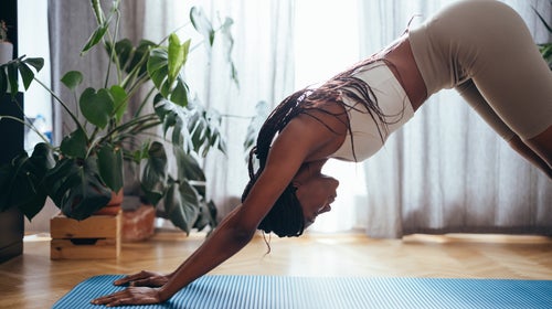 Side view of African-American woman in sportswear practicing yoga in the morning