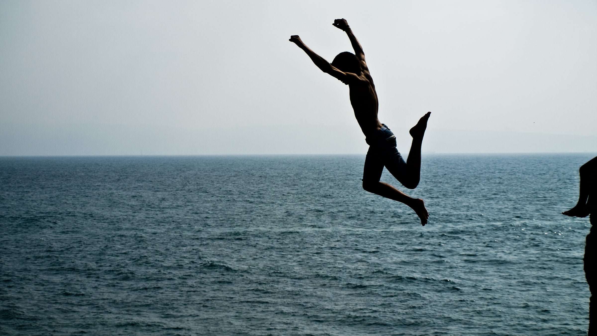 A man jumps off a cliff. 