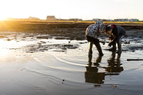 Elementary-aged Brent Iyatunguk and Elmer Olanna scour the inland beach for minnows.