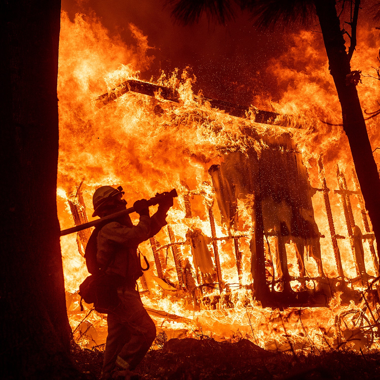 Firefighter Jose Corona sprays water as flames from the Camp Fire consume a home in Magalia, California.