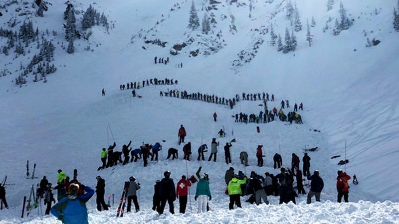 Rescuers form lines to probe for people buried in an avalanche at the bottom of Kachina Peak on Thursday.
