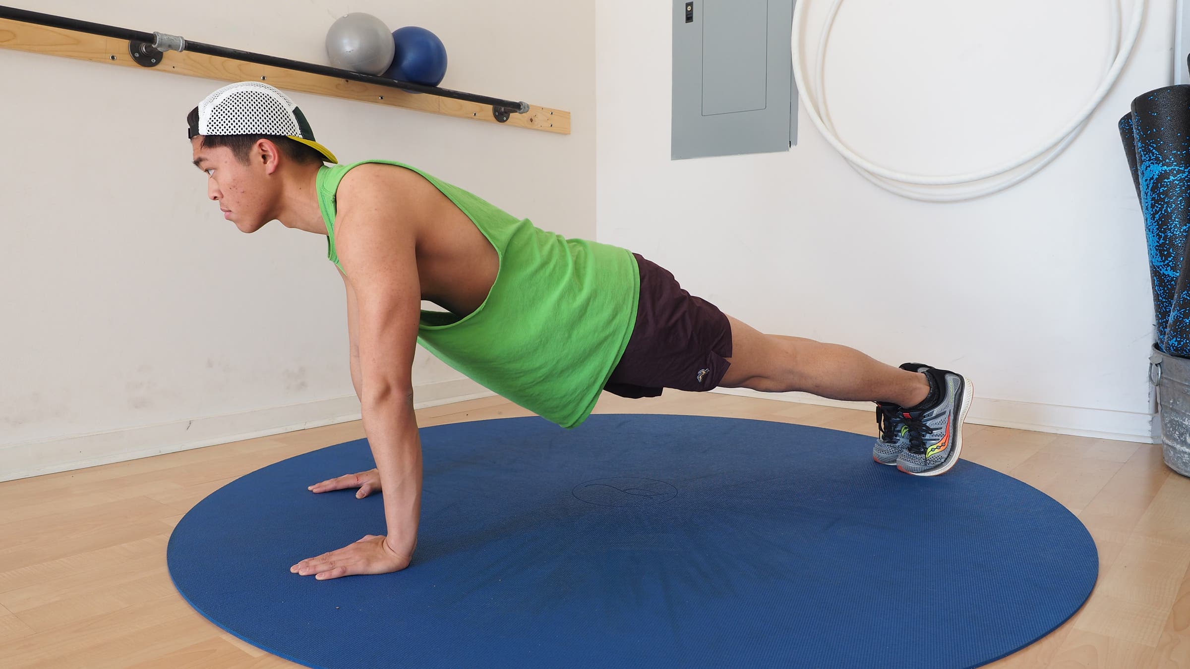 man holding top of push-up position in gym on blue mat