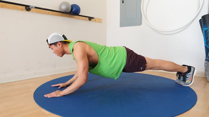 man rising halfway from elbow plank to full plank