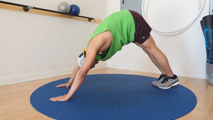 man in downward dog position in gym