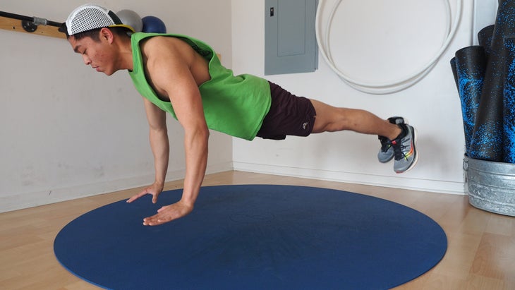 man in high plank form hovering above ground in gym