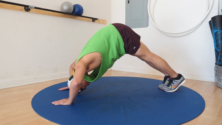 man in downward-dog push-up, with arms bent, in gym