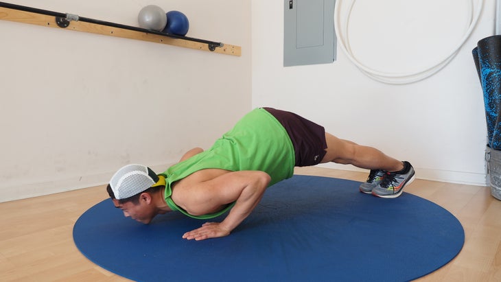 man in green shirt pushing chest to ground while backside is still up in plank position