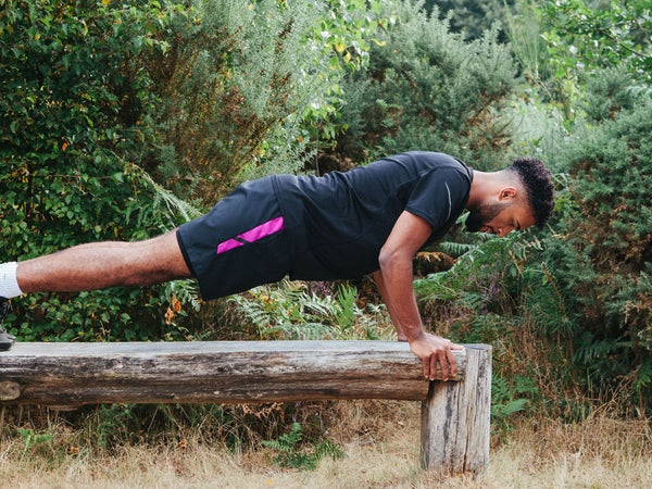 man holding push-up position on a wooden bench