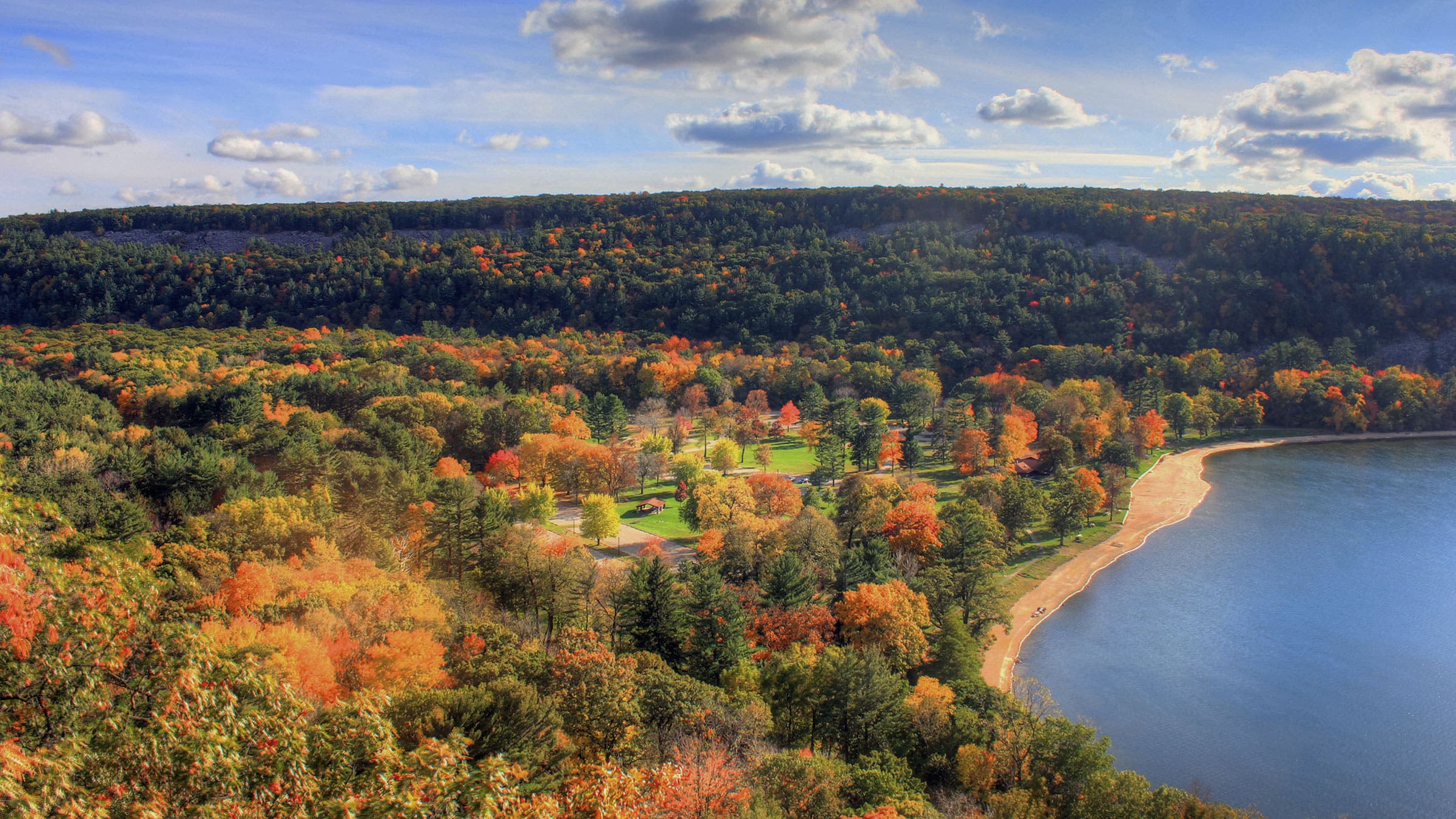 trees with fall colors over a blue lake