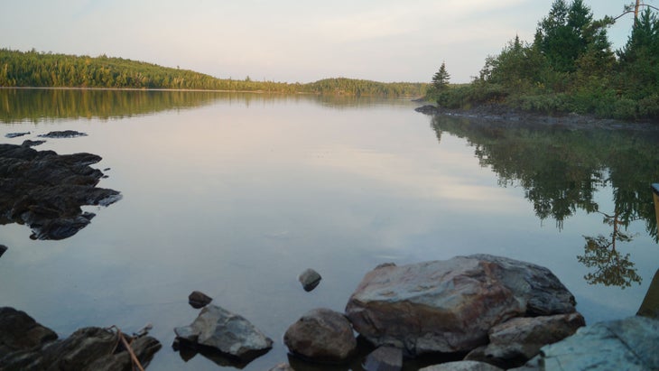 beautiful lake with big rocks and trees at sunrise or sunset