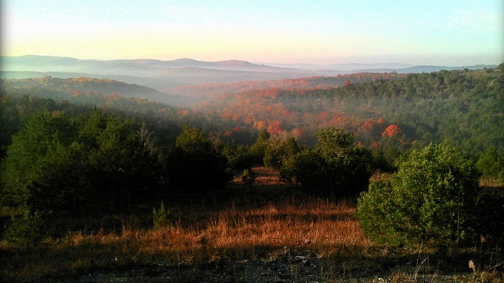 misty sunrise over woods and mountains in the distance in fall