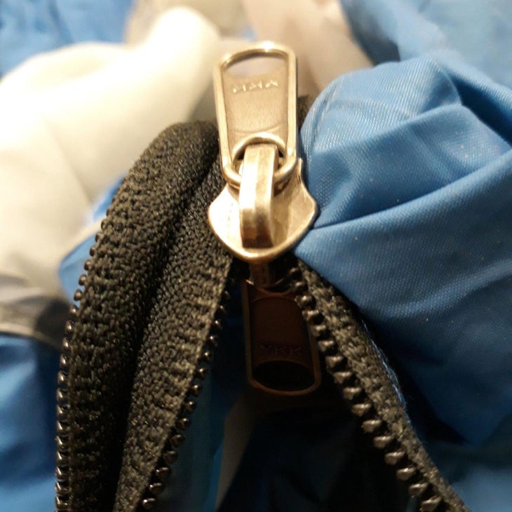 close-up of a zipper caught on a blue jacket on the right side