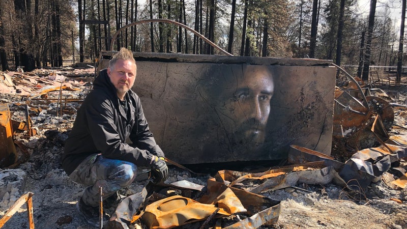 Shane Grammer in front of a mural on the baptismal font of a destroyed church in Paradise