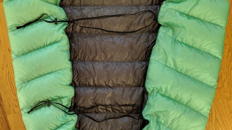 On the back of the AstraLite, there are three 3/8-inch elastcized grosgrain webbing loops. (I removed one.) A sleeping pad can be inserted into them, to create a tighter seal between the quilt and pad.