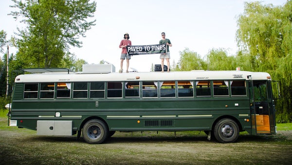 Mitchell Rosko and Steven Glass stand on top of one of their school bus conversions.