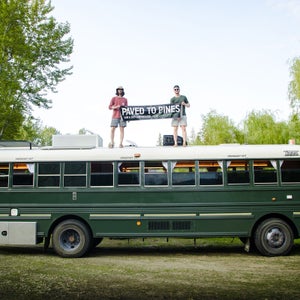 Mitchell Rosko and Steven Glass stand on top of one of their school bus conversions.