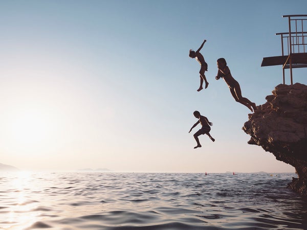 Silhouette of a group of children jumping from a cliff.