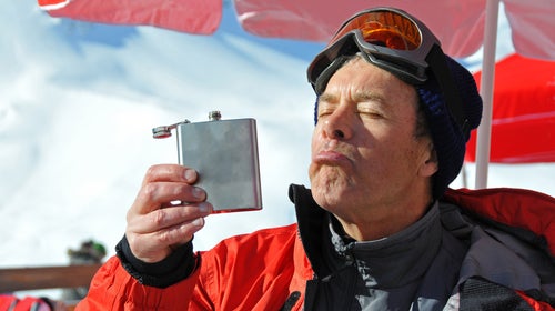 Senior man drinking out of hip flask in winter