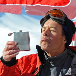 Senior man drinking out of hip flask in winter