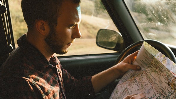 Man sitting in a car looking at a map