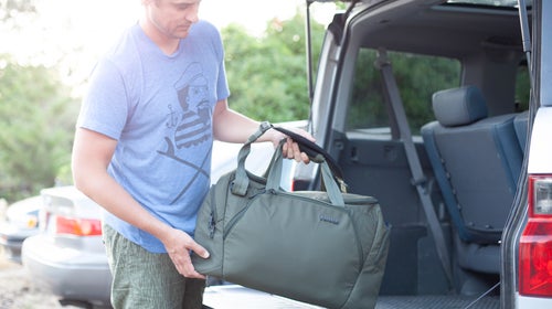 Man putting a duffel bag into the trunk