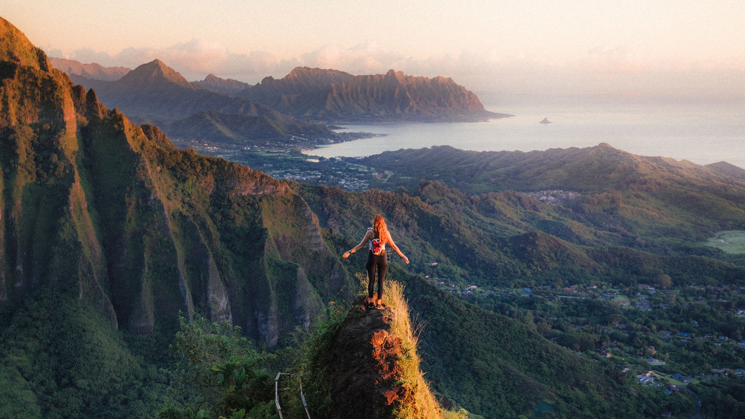 woman standing on ridge at sunset on oahu overlooking pacific ocean hawaii