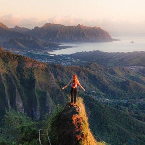 woman standing on ridge at sunset on oahu overlooking pacific ocean hawaii