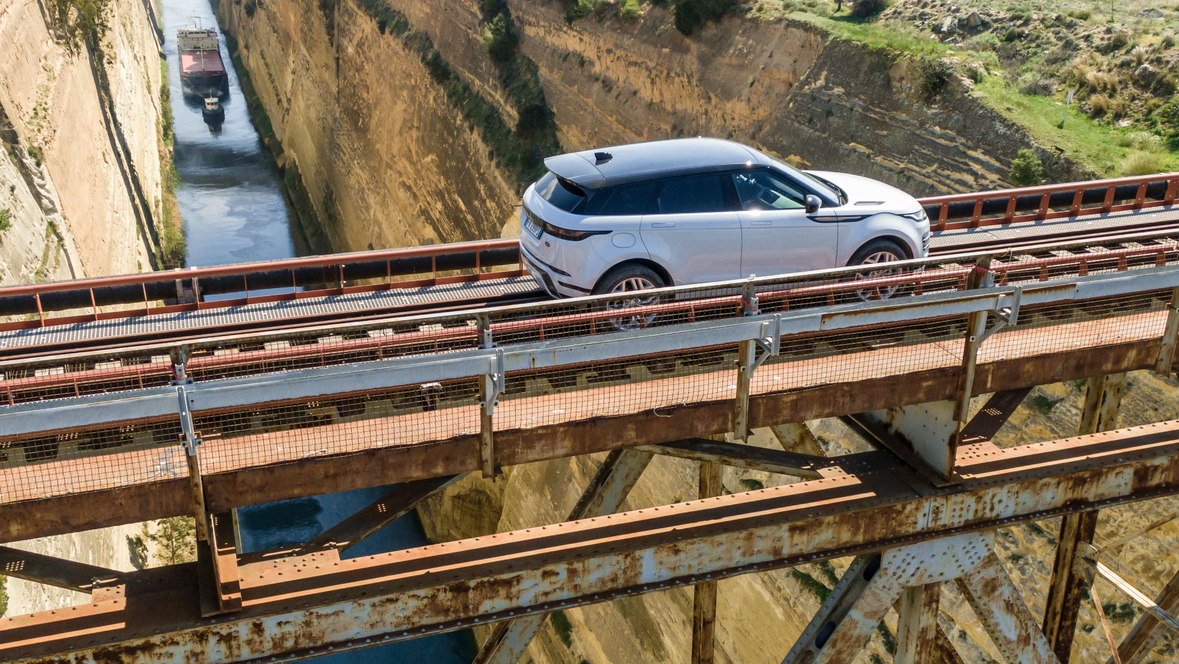 The Evoque crosses a railroad bridge over a canal in Greece. 