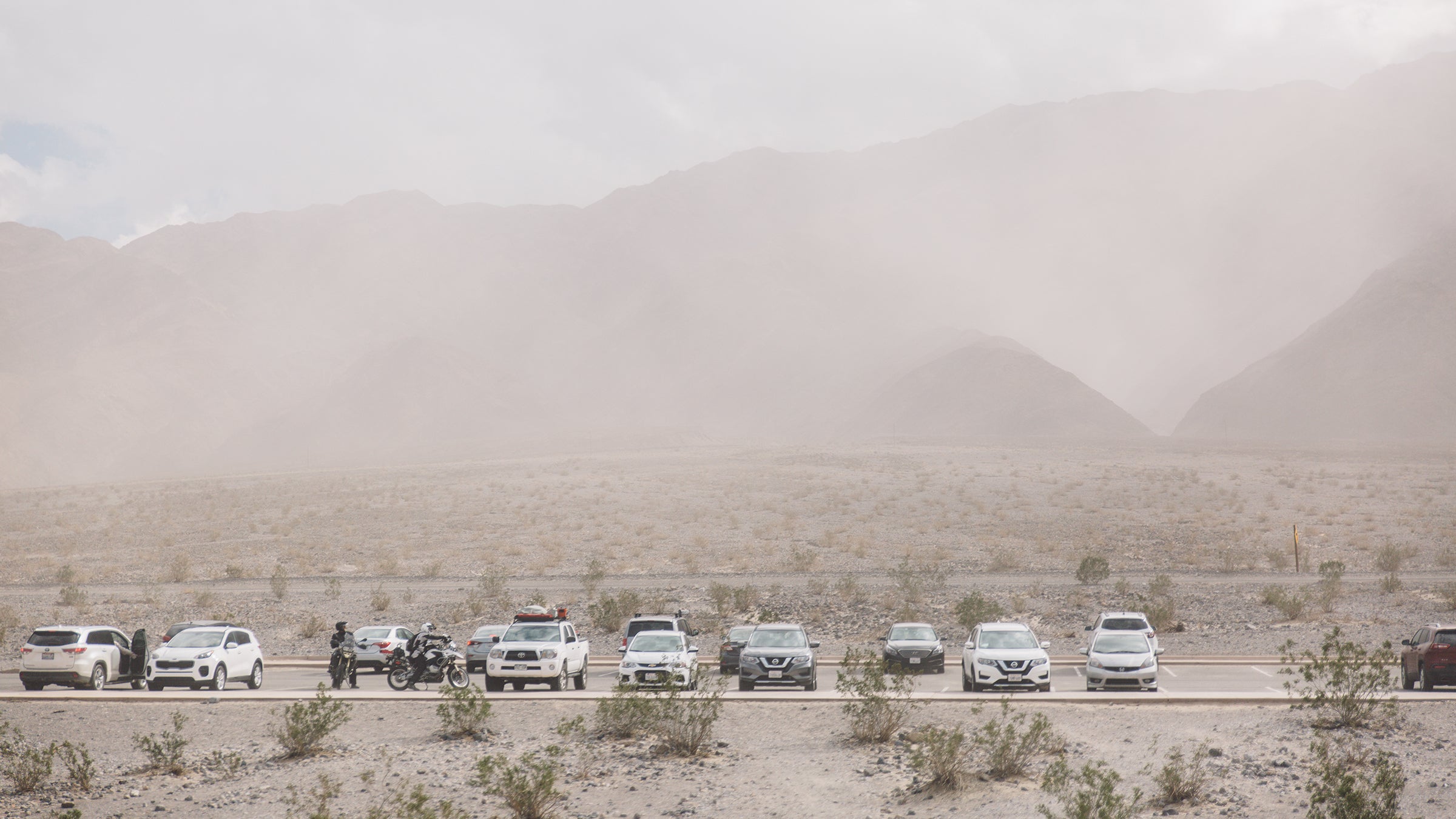 Vehicles Parked At Parking Lot Against Mountains At Death Valley During Sandstorm