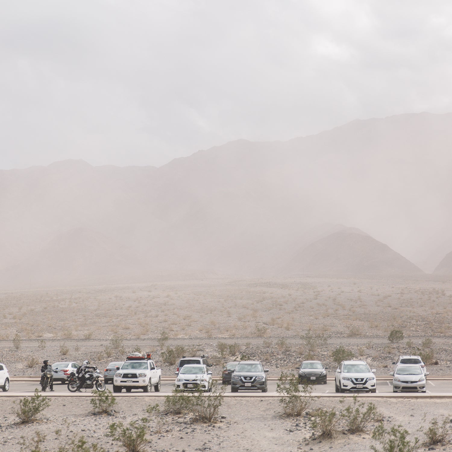 Vehicles Parked At Parking Lot Against Mountains At Death Valley During Sandstorm