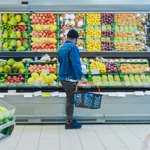 At the Supermarket: Happy Black Stylish Guy with Shopping Basket Shopping for Organic Fruits and Vegetables in the Fresh Produce Section of the Store.