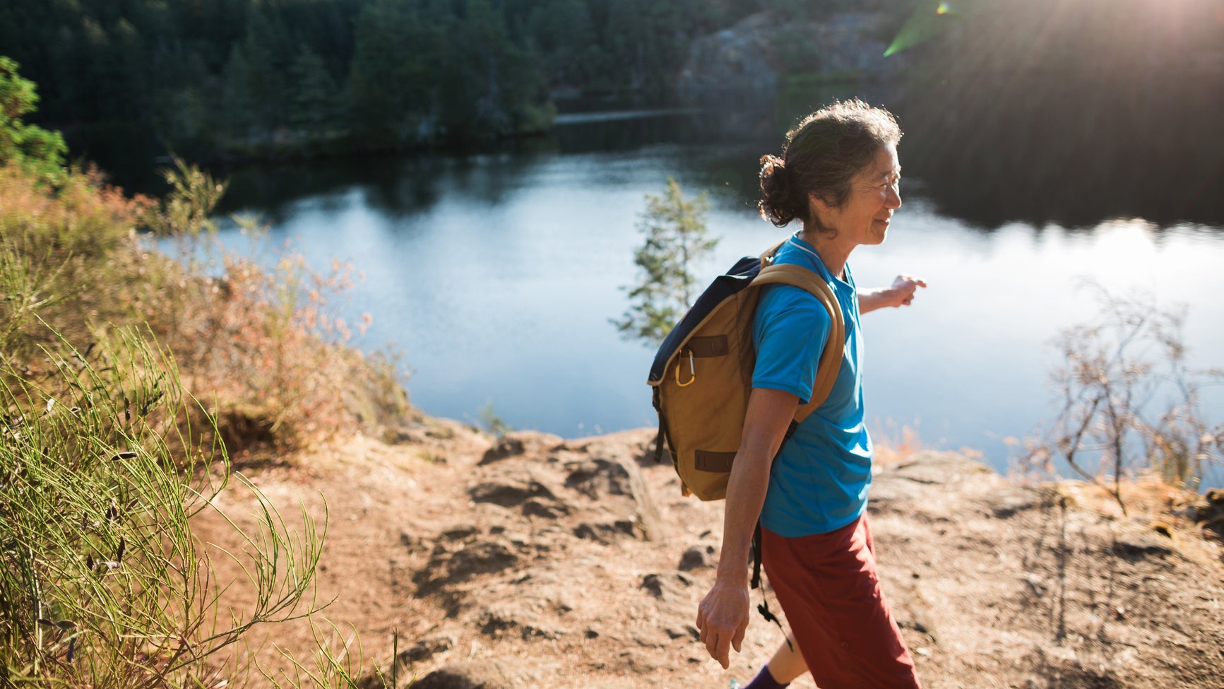 Content Mature Woman Hiking Near Lake At Sunrise