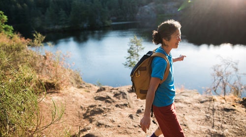 Content Mature Woman Hiking Near Lake At Sunrise