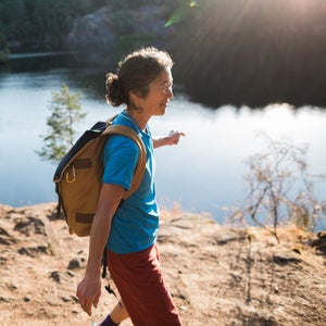 Content Mature Woman Hiking Near Lake At Sunrise