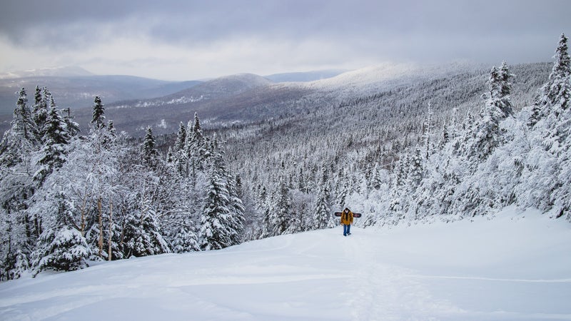 A snowboarder hiking near the warming hut on Saddleback in 2017