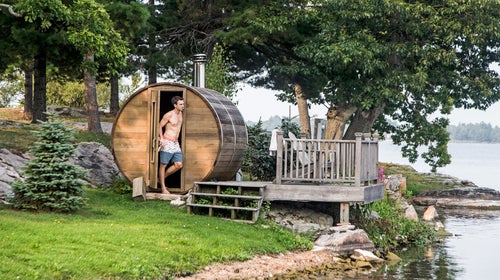 A man stands next to a backyard sauna along the St. Lawrence River in upstate New York's 1000 Islands.