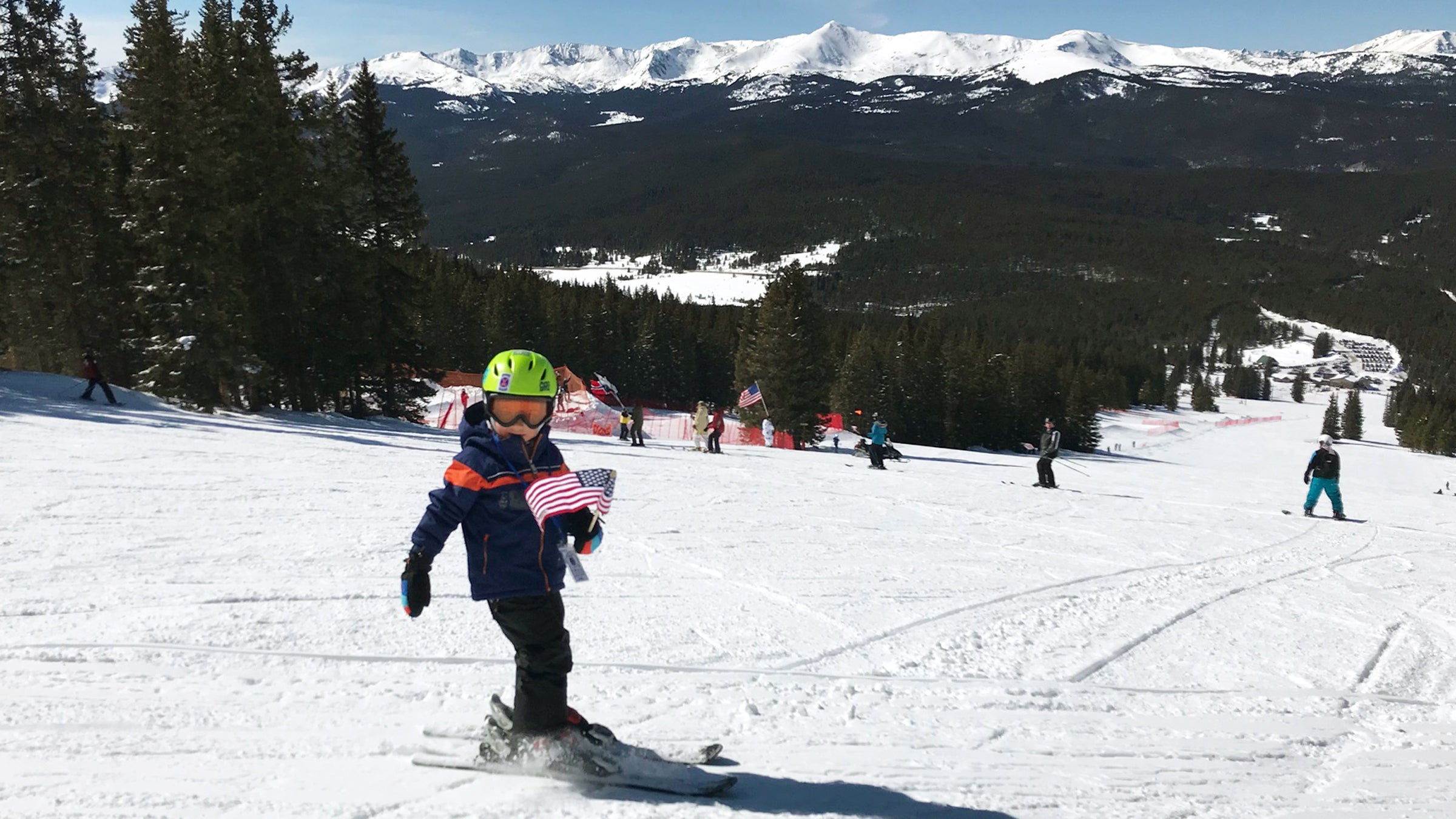 The author’s son Lachlan holding an American flag as he and others participate in an event called “skiing the serpentine”; everyone follows the person in front of them in a giant snake formation until they reach the bottom of the hill.