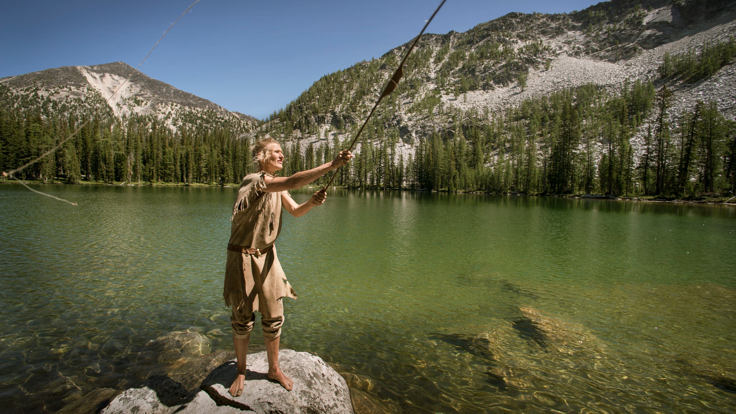Lynx casts a fishing line made of dogbane attached to her hunting bow in a lake near her home in Twisp, Washington.