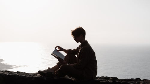 Woman Sitting On High Mountains Hills And Reading.