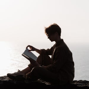 Woman Sitting On High Mountains Hills And Reading.