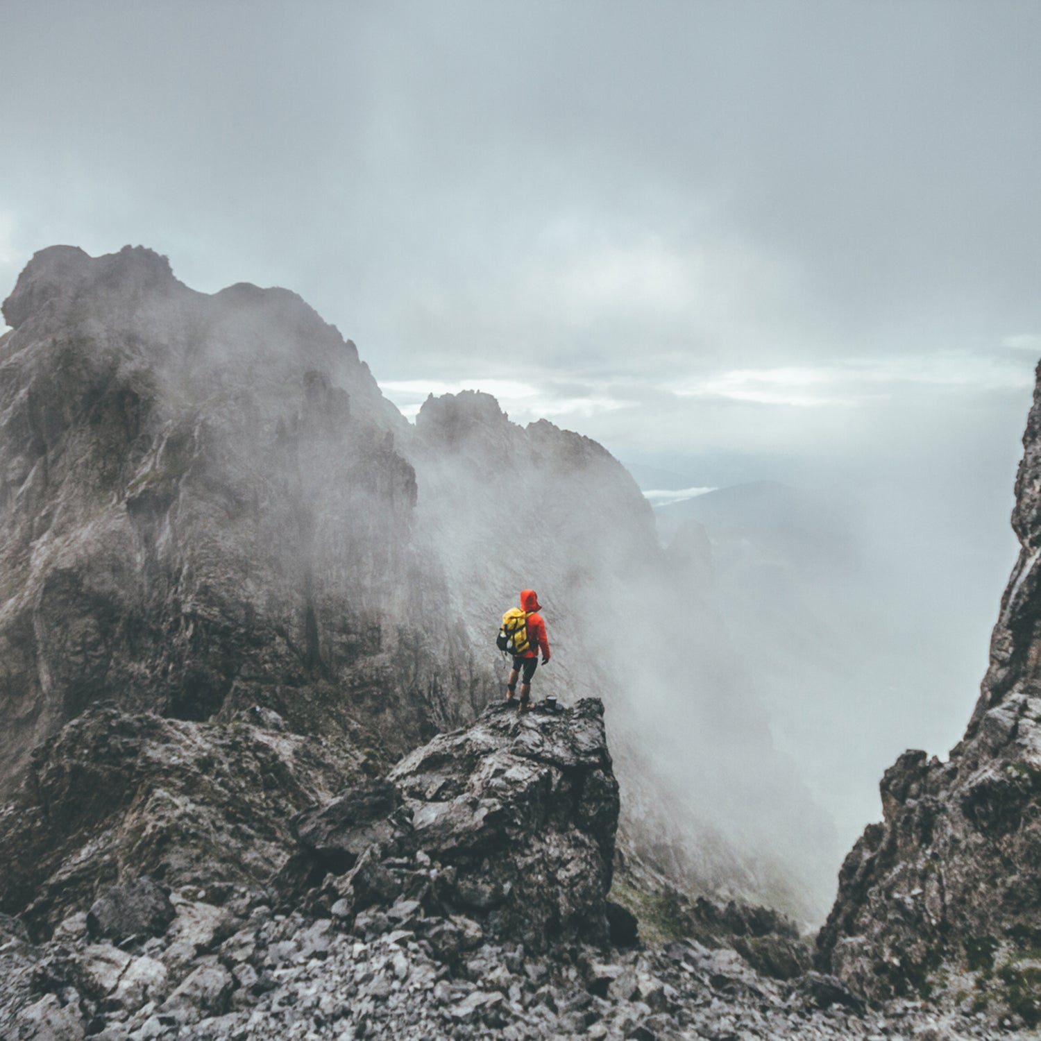 Male Mountaineer Standing On Top Of A Mountain In A Rugged Landsape