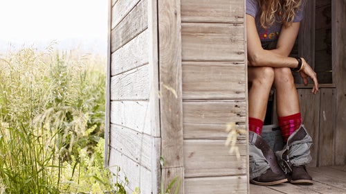 Woman on toilet in outhouse