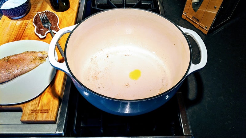 With the stove on high, add a small drop of olive oil to the pan, and wait for it to begin smoking. This drop of oil isn't for flavor, or for cooking (the chicken is already rubbed in oil), it's just there to indicate temperature, so you don't need much at all.