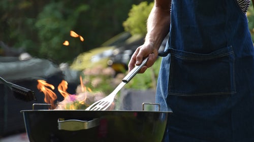 Male arm holding a spatula over a grill
