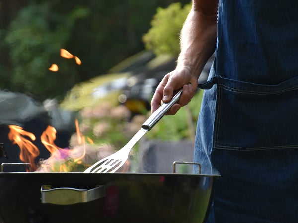 Male arm holding a spatula over a grill