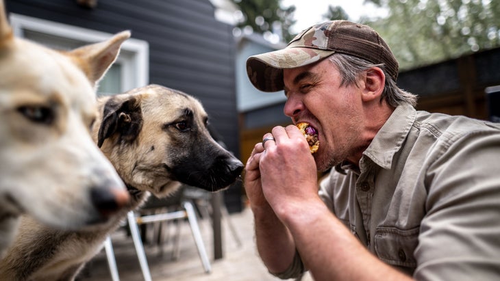 Wes Siler eats a burger with his two dogs.