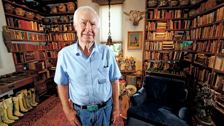 Forrest Fenn posing for a photo in a bookshelf-filled room in his home in Santa Fe in 2014