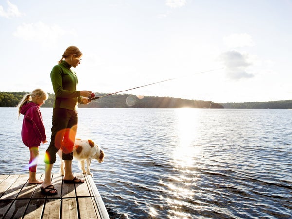 Mother Daughter And Dog Fishing From Dock At Cottage